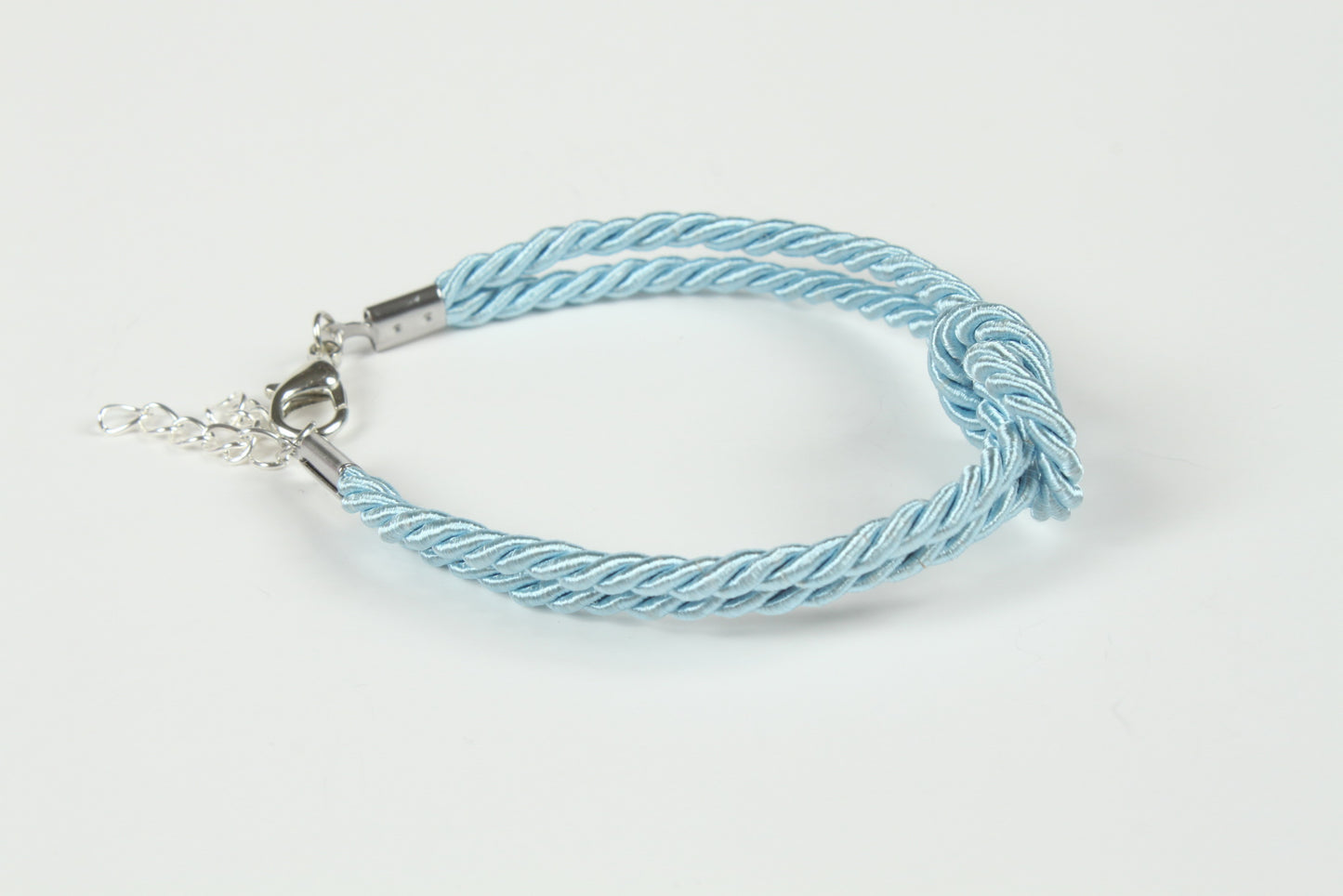 Flat lay of pastel blue rope bracelet with polished metal end caps