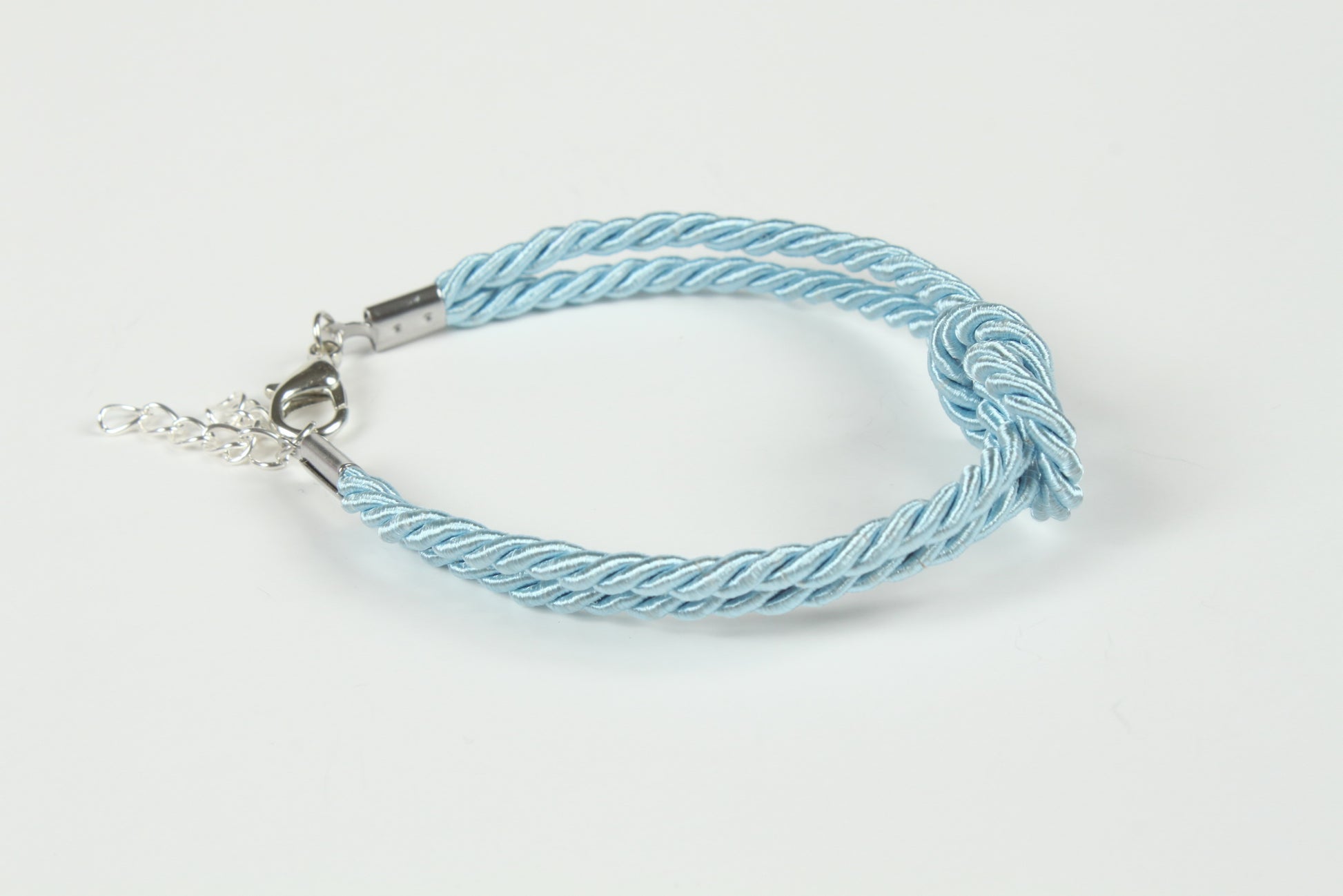 Flat lay of pastel blue rope bracelet with polished metal end caps