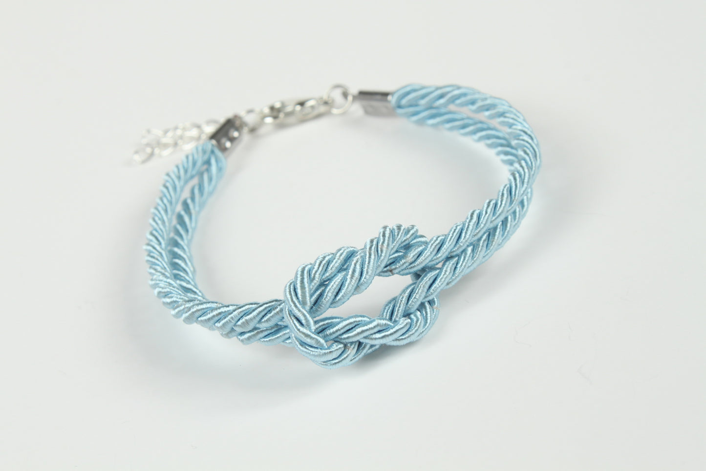 Blue rope bondage bracelet photographed against white background