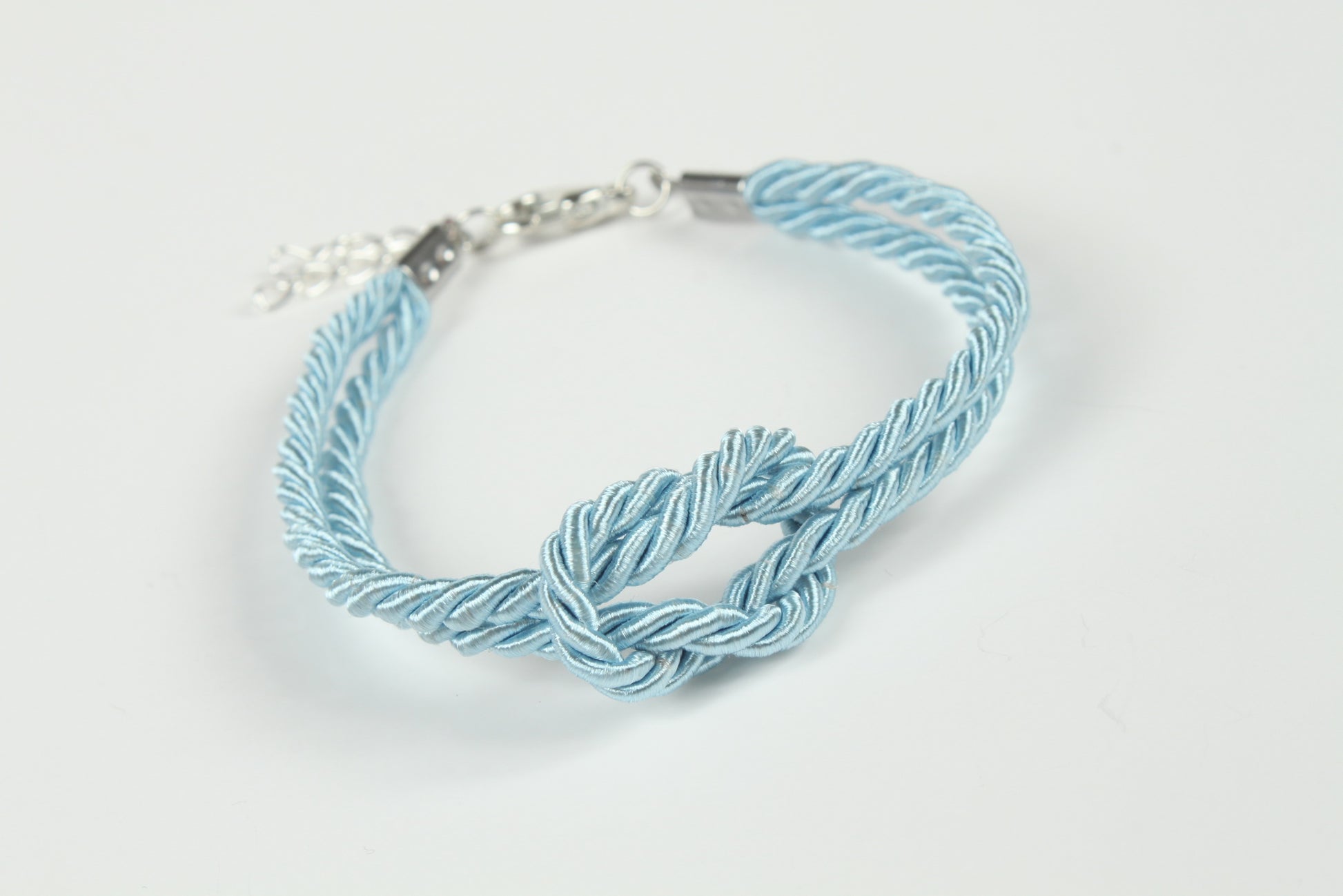 Blue rope bondage bracelet photographed against white background