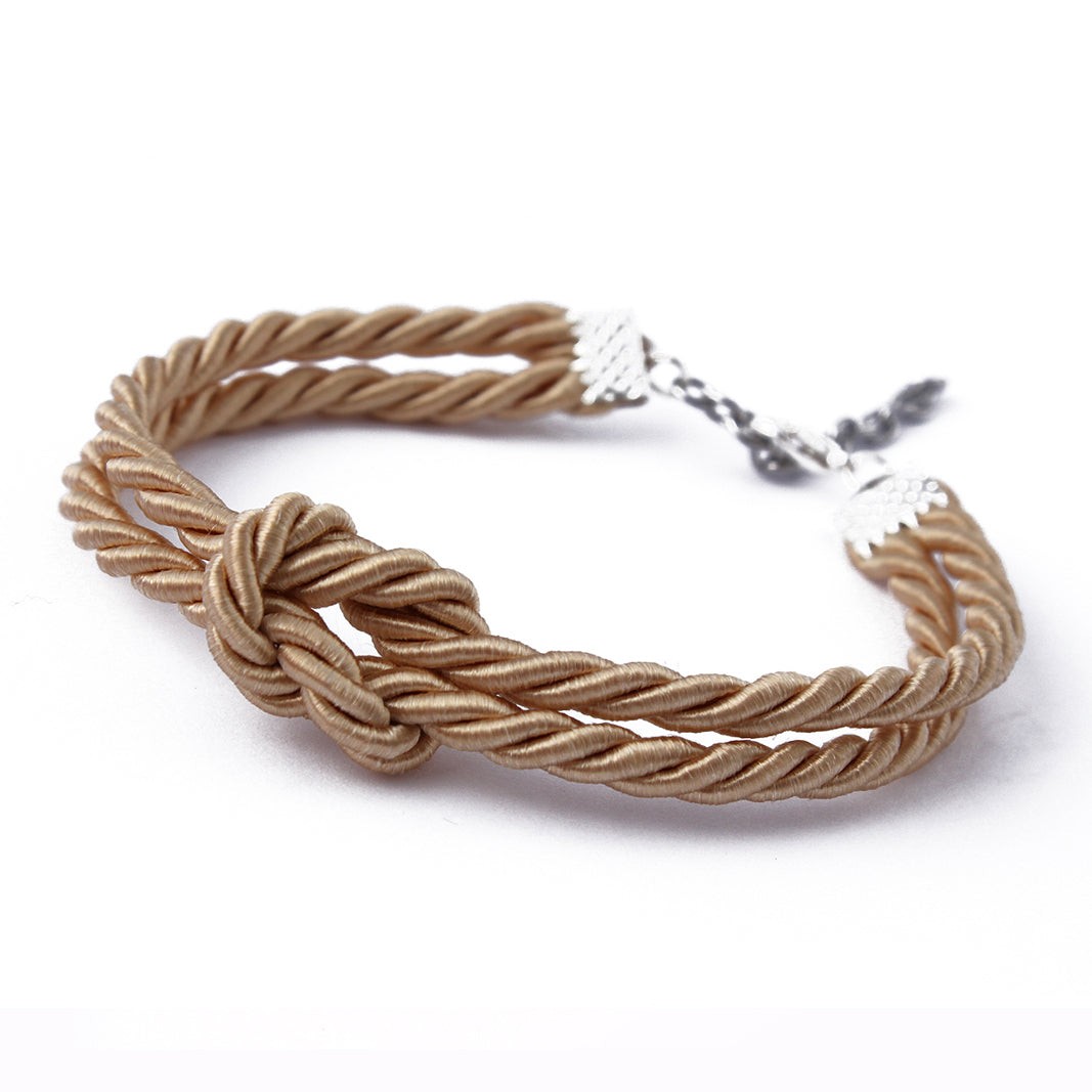 Close-up of a delicate gold rope shibari bracelet, showcasing the intricate weave